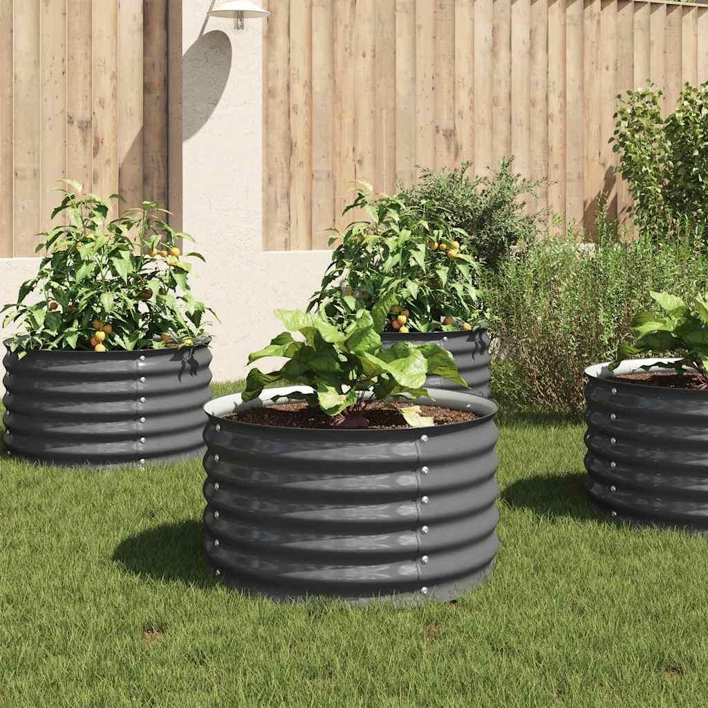 Four raised garden beds filled with plants are arranged on a grassy lawn in front of a wooden fence.