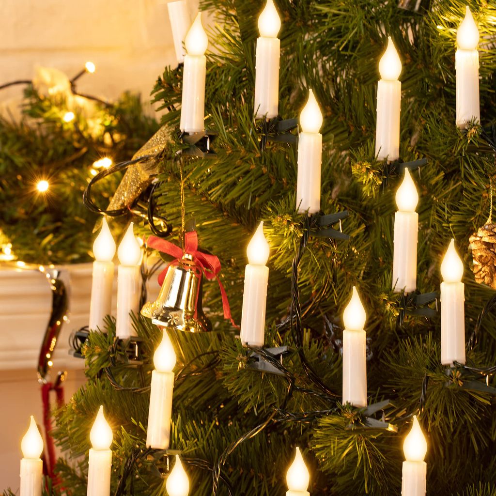 A close-up view of a decorated Christmas tree with LED candle lights and a bell ornament.