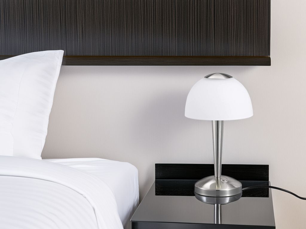 A bedside lamp on a nightstand next to a bed.