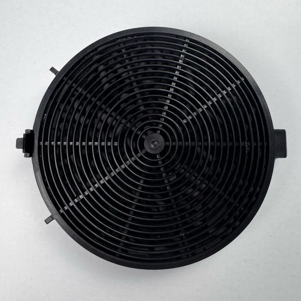 A top-down view of a black circular carbon filter for a range hood.