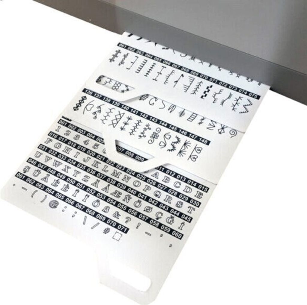 A close-up view of a perforated card with lines of stitch patterns and alphanumeric characters, likely for a sewing machine, emerging from a machine.