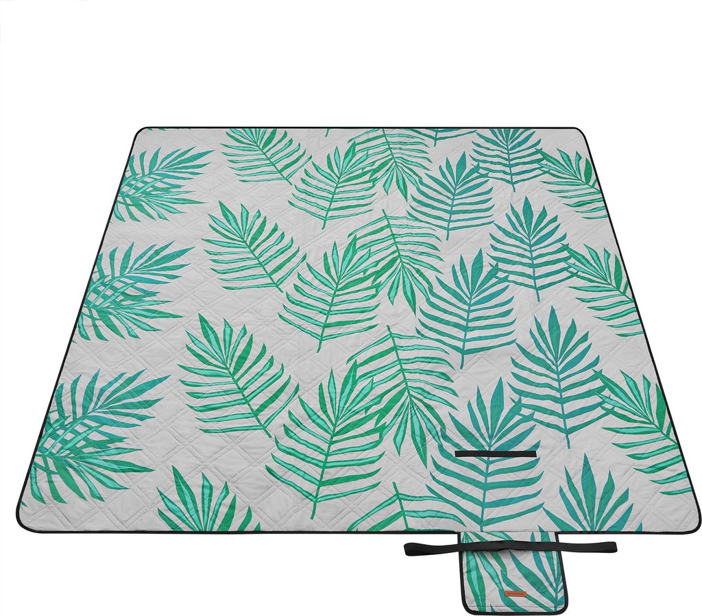A picnic blanket with a tropical fern pattern is laid out flat on a white background.
