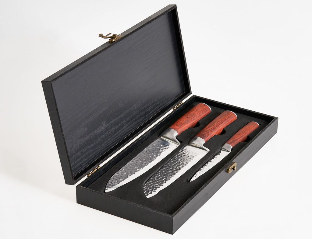 A set of three knives with wooden handles are displayed in an open black wooden box.