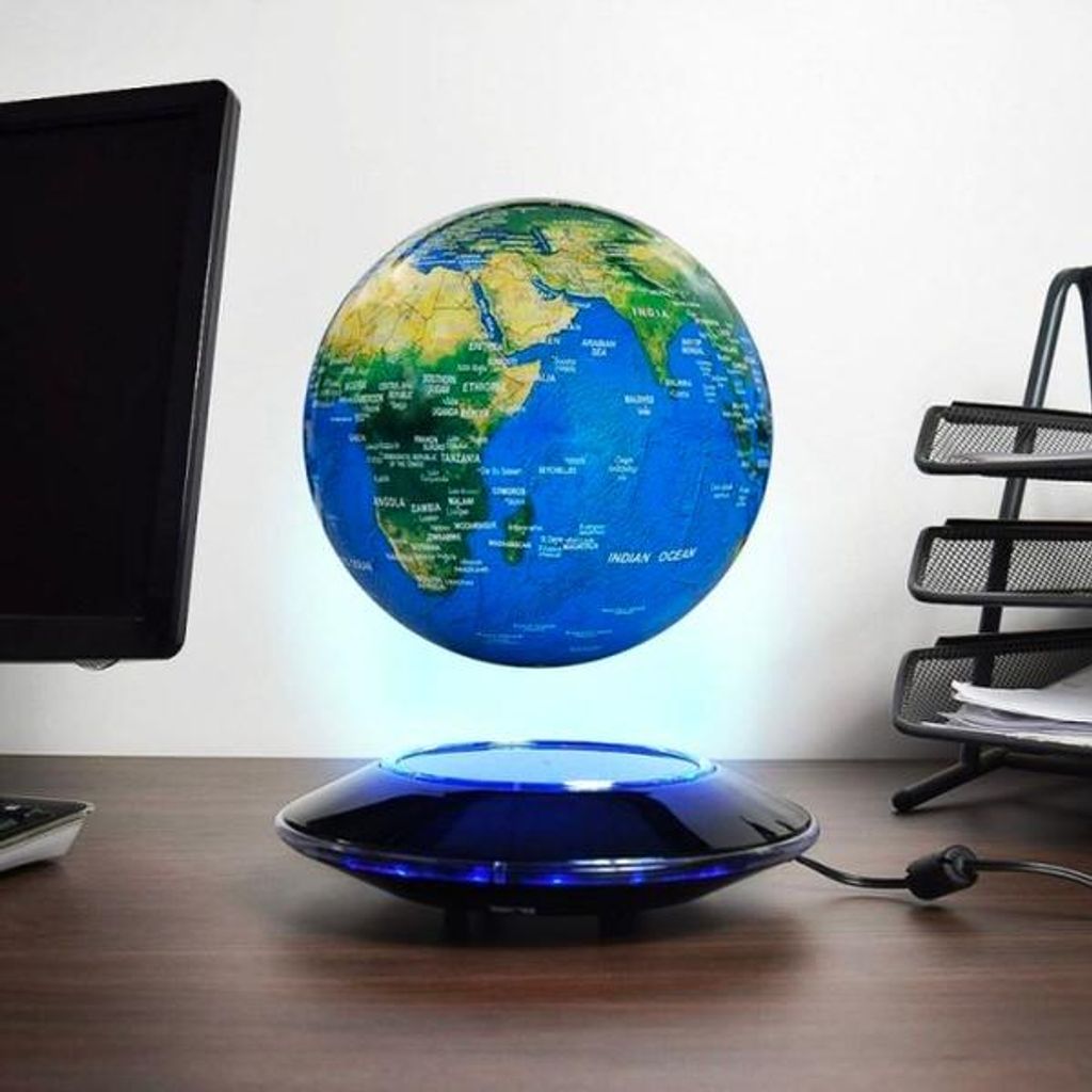 A floating globe on a desk with a computer monitor and a document holder.