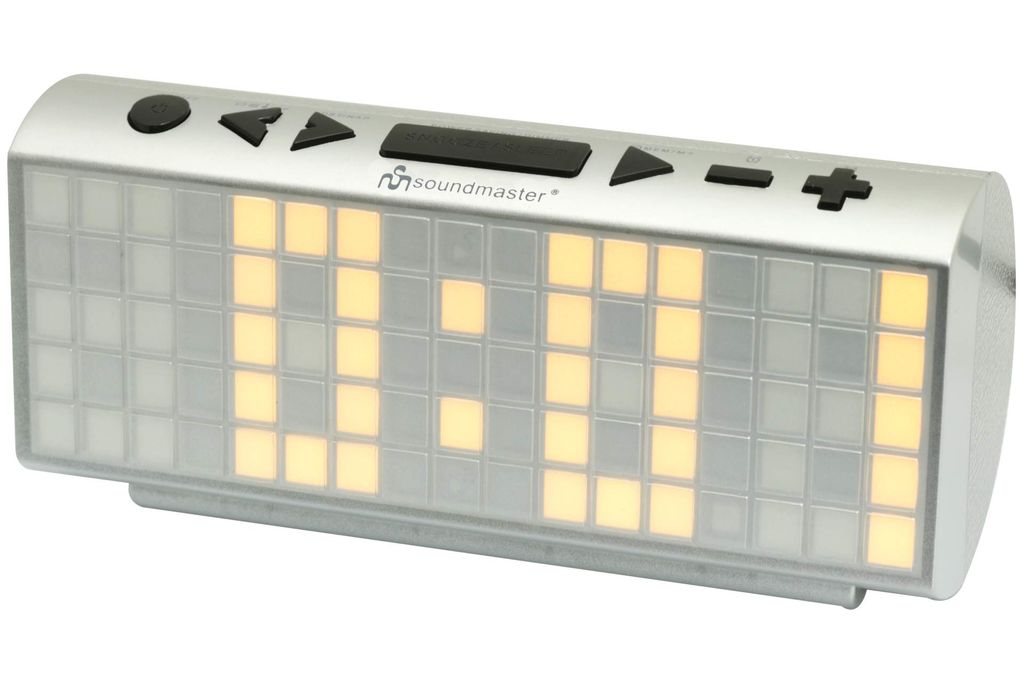 A silver and white digital alarm clock with a large LED display showing yellow digits.