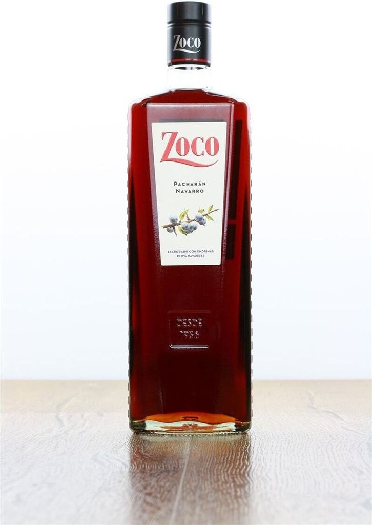 A bottle of Zoco Pacharan liqueur stands on a wooden surface against a white background.