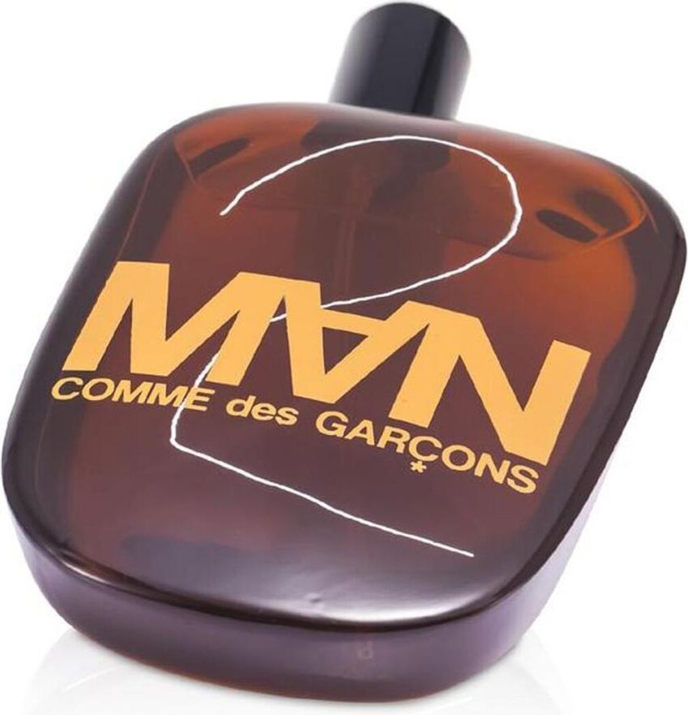 A brown glass perfume bottle with an orange label and a black cap, set against a white background.