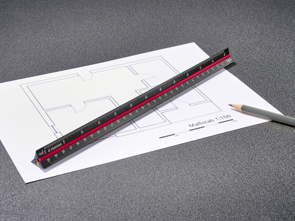 A triangular ruler is placed on a blueprint with a pencil nearby.