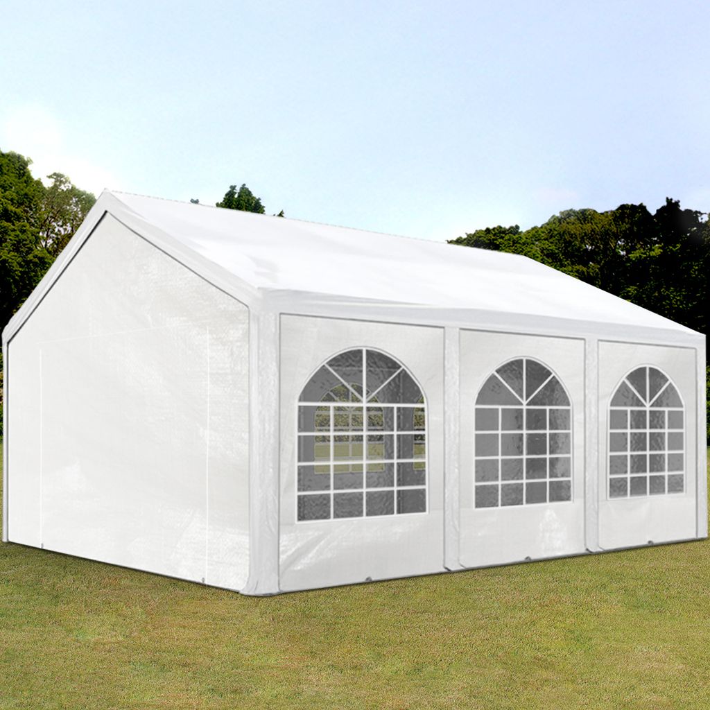 A white party tent is set up on a grassy lawn with trees in the background.