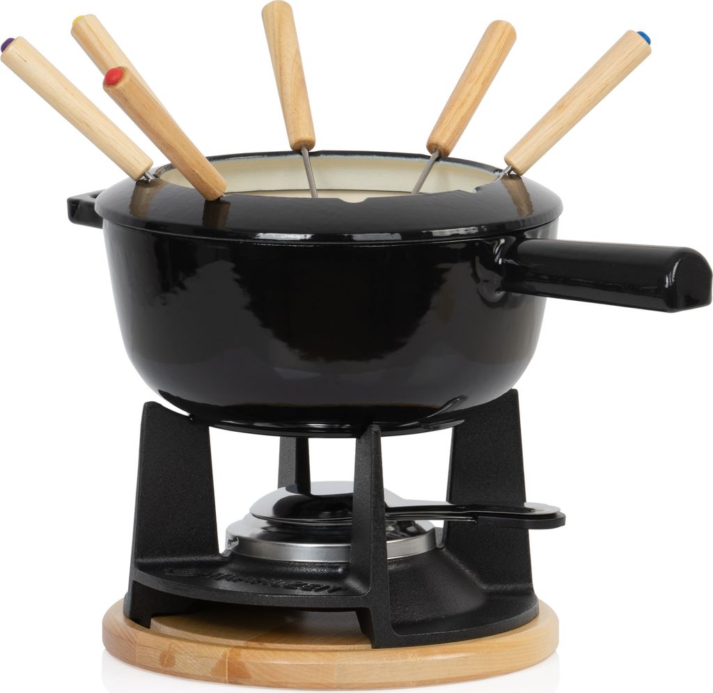 A black cast iron fondue set with wooden-handled fondue forks sits on a wooden base above a burner.