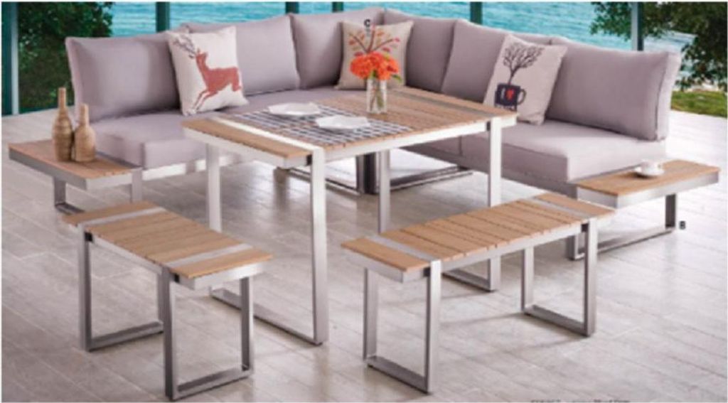 An outdoor lounge set with a sectional sofa, table, and benches, set on a patio with a view of water and trees.