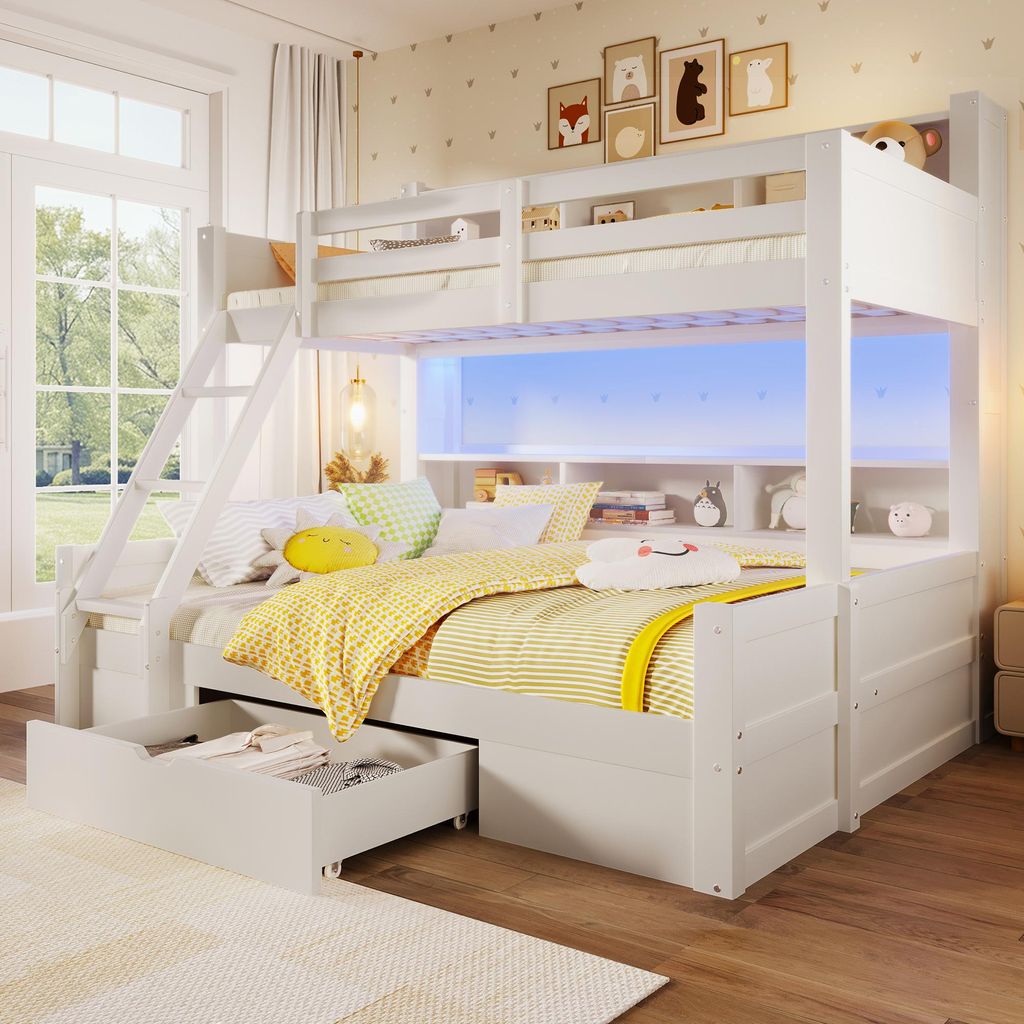 A white bunk bed with a pull-out drawer and storage shelves, decorated with colorful bedding and stuffed animals, in a child's bedroom.
