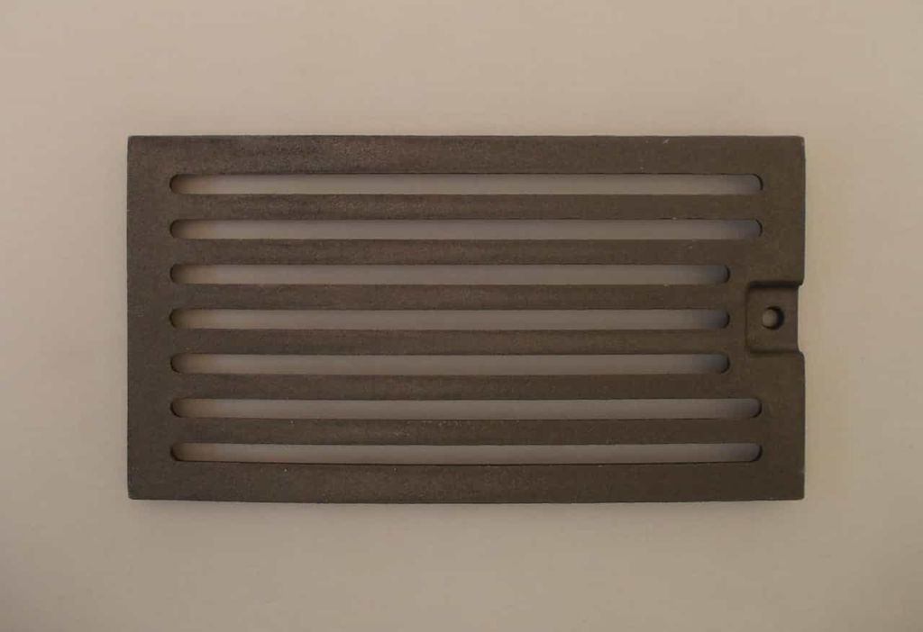 A rectangular cast iron grate with horizontal slots, placed on a light gray background.