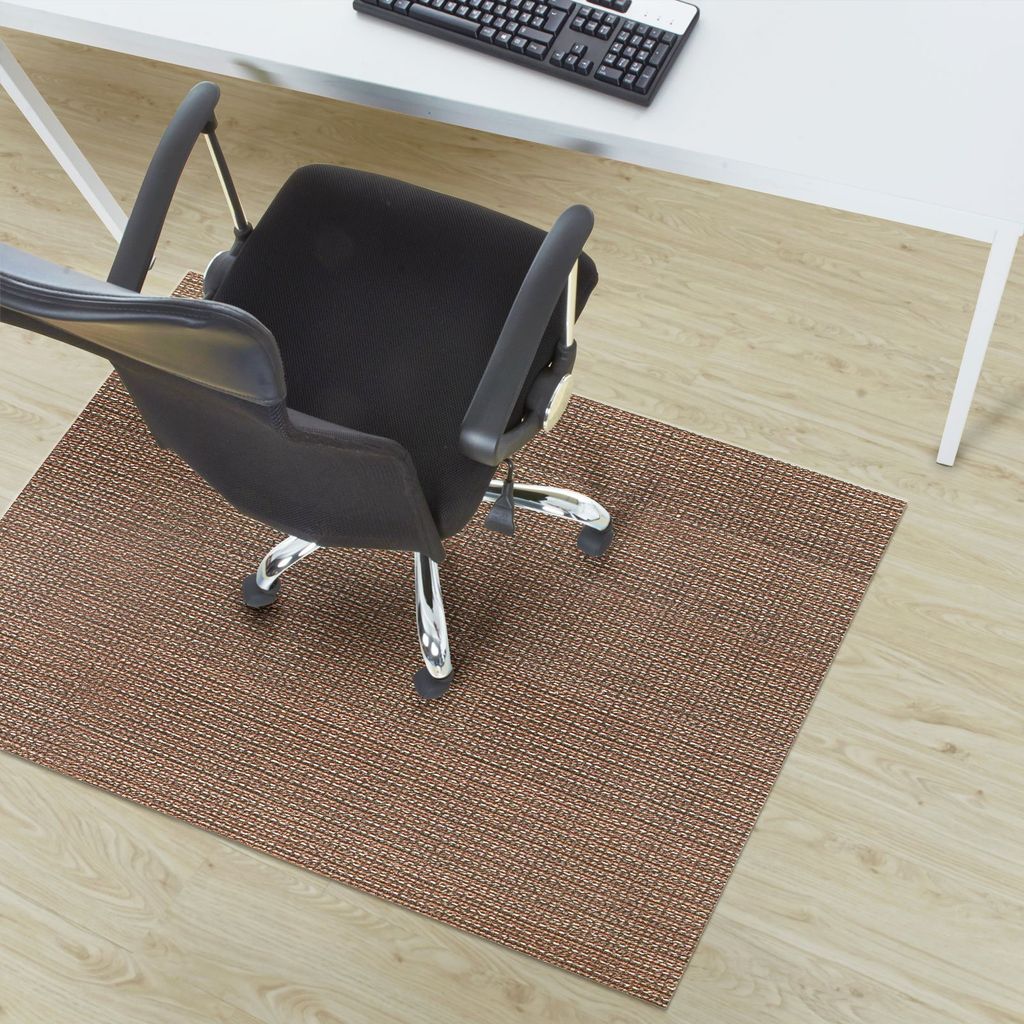 An office chair on a brown floor mat in front of a white desk.