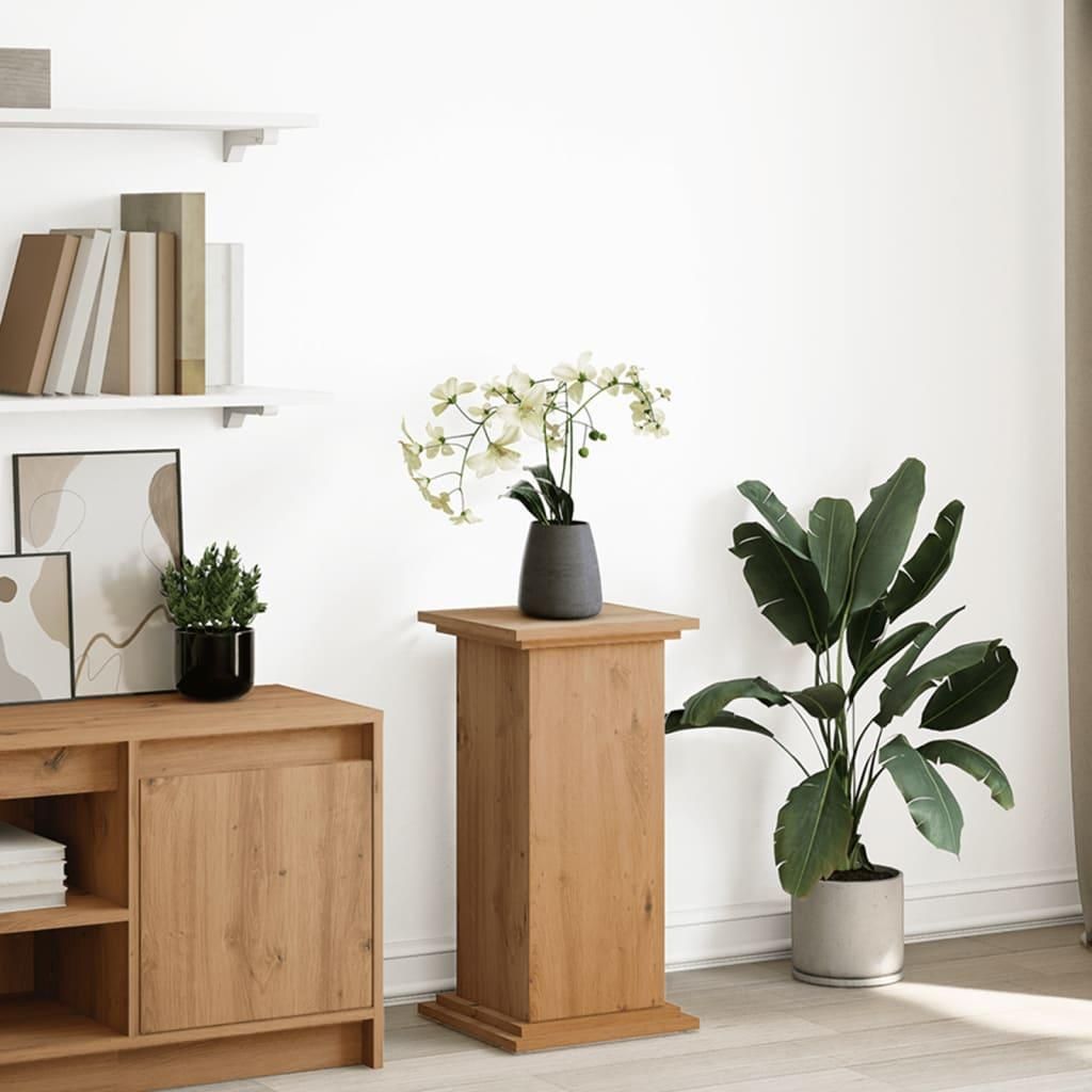 A wooden pedestal with a vase of flowers and a potted plant next to it, placed in a room with shelves and a cabinet.