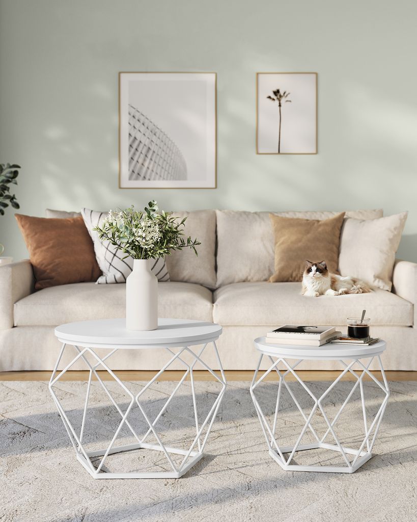 A living room scene with a sofa, coffee tables, and wall art.