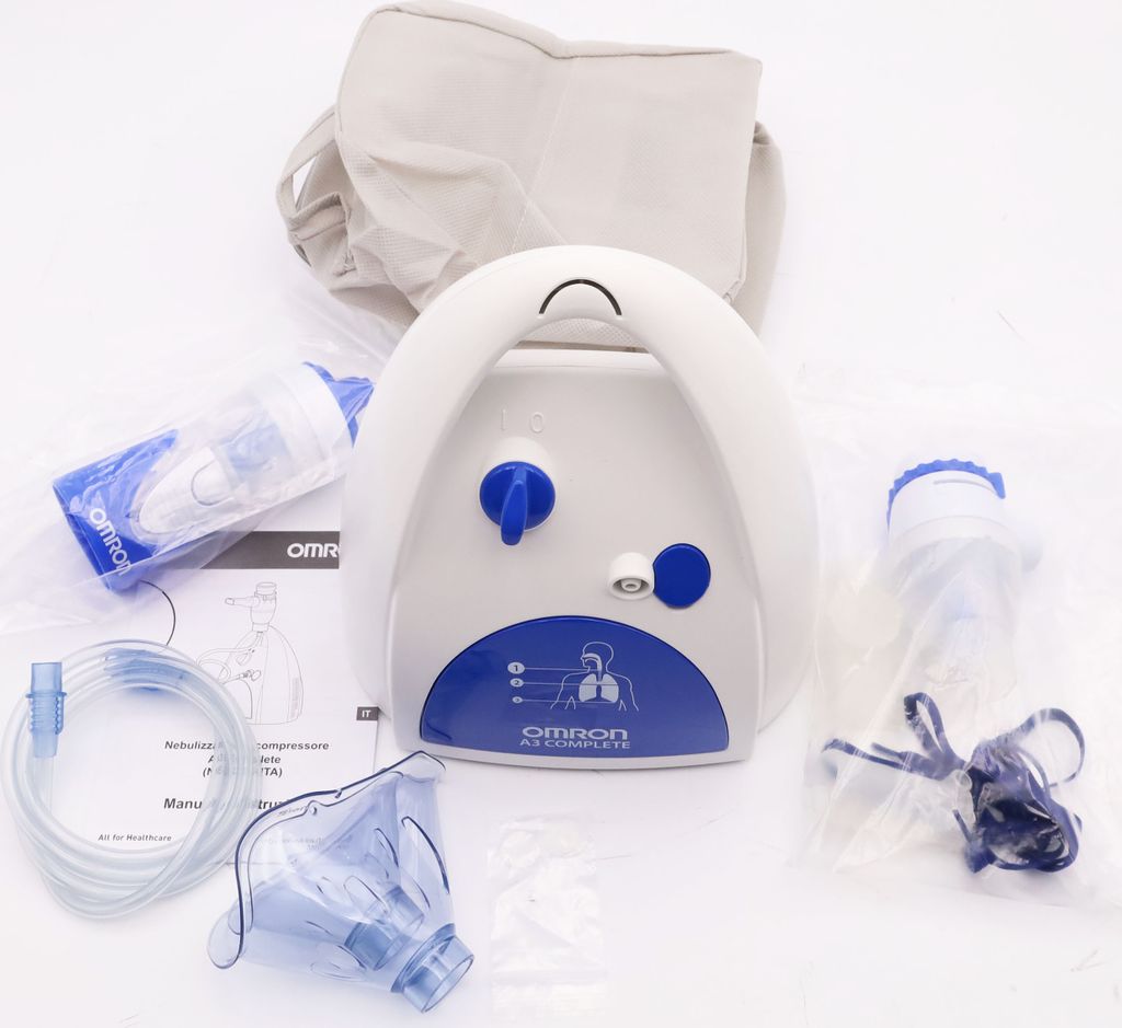 An OMRON A3 nebulizer kit is laid out on a white surface, with its various components including the main unit, mask, tubing, and a carrying bag.
