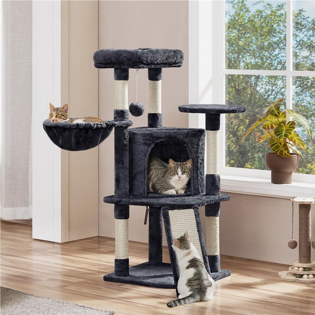 Three cats are interacting with a multi-level cat tree in a room with a window.