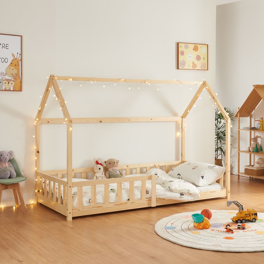 A child's bedroom with a wooden house bed, toys, and decorations.