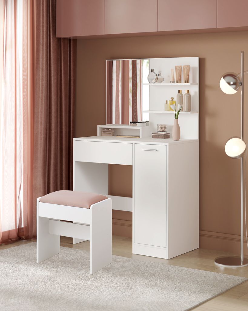 A white vanity set with a mirror and stool in a room with pink and brown accents.