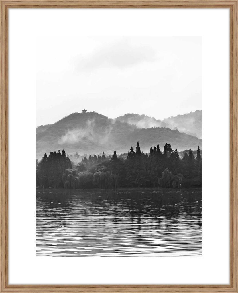 A framed black and white landscape photograph of mountains, trees, and a lake.