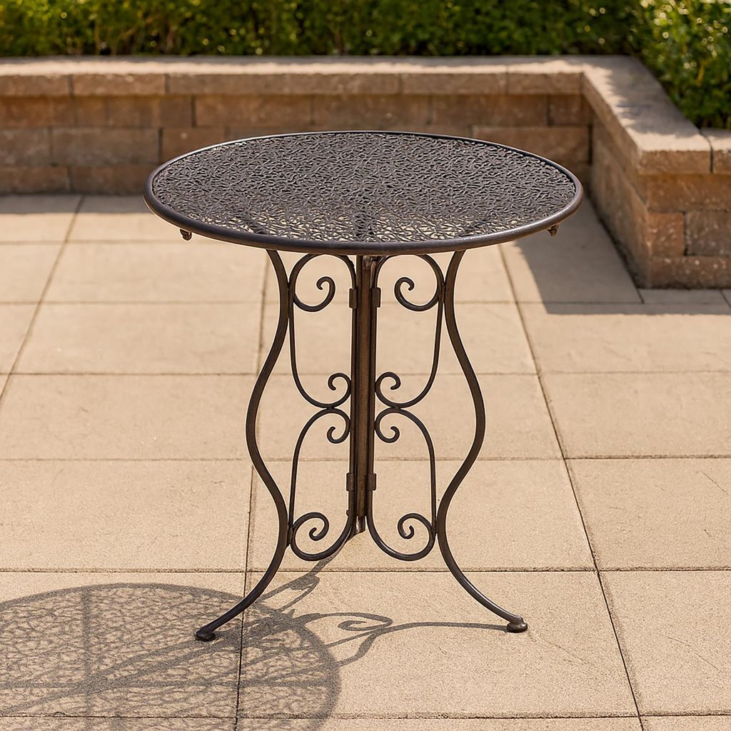 A round metal garden table with an ornate base is shown on a paved patio.