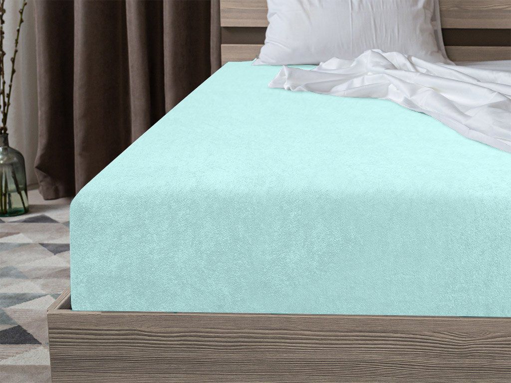 A close-up view of a mint green fitted sheet on a bed.