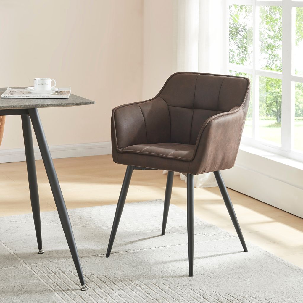 A brown upholstered dining chair with black metal legs sits next to a table in a well-lit room with a window.