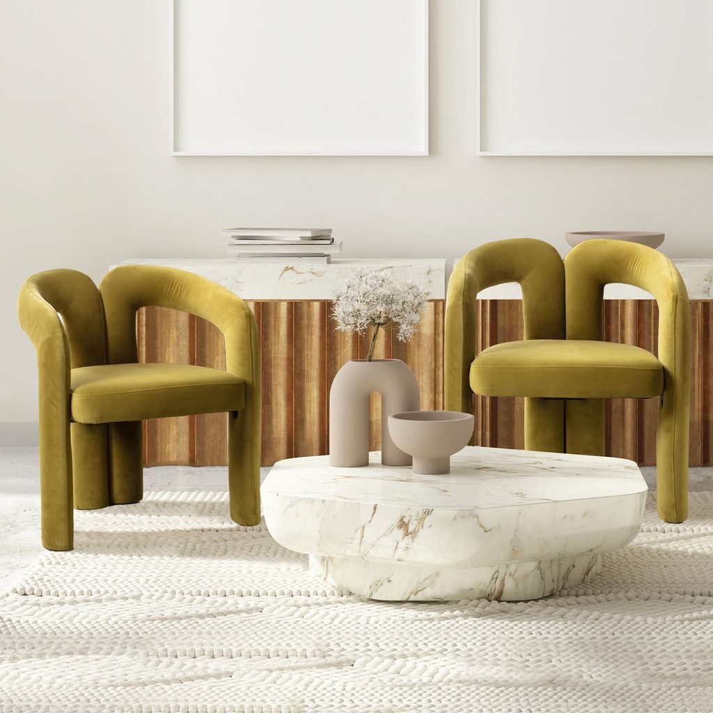 Two olive-colored velvet chairs are placed in a living room setting with a marble coffee table and a wooden cabinet in the background.