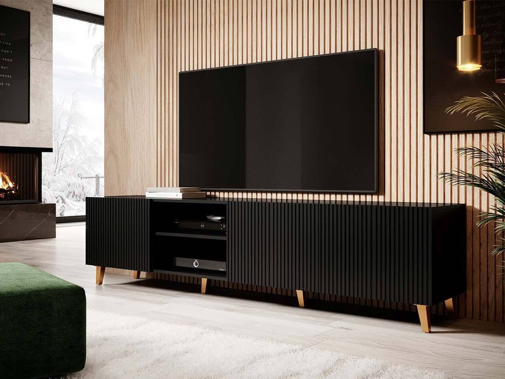 A modern living room with a fireplace, a large TV on a black media console, and a green ottoman.