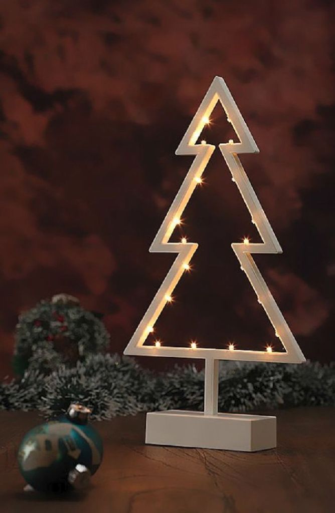 A decorative Christmas tree light on a wooden surface with a blurred background.