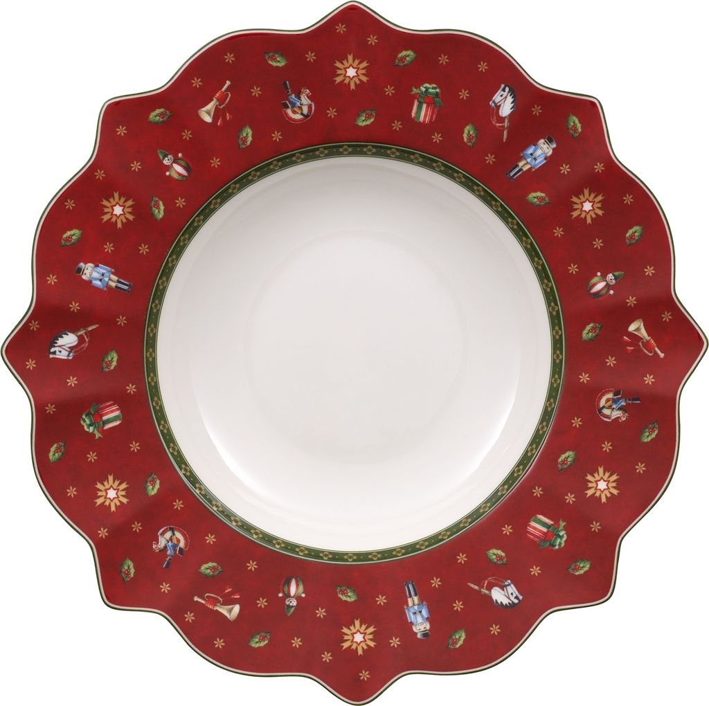 A top-down view of a round, scalloped-edge soup plate with a red background decorated with small Christmas-themed motifs like nutcrackers, gifts, and snowflakes. The center of the plate is white.
