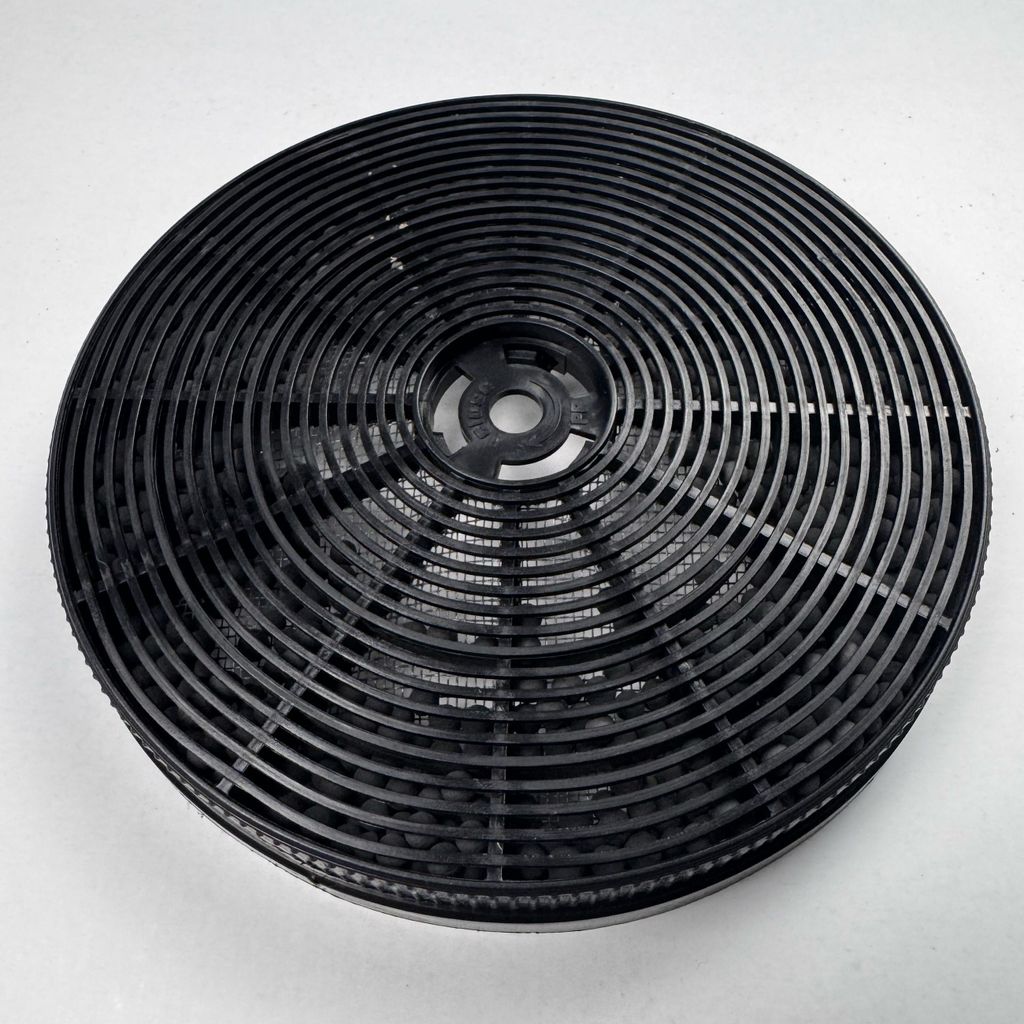 A close-up overhead shot of a black circular charcoal filter for a range hood.