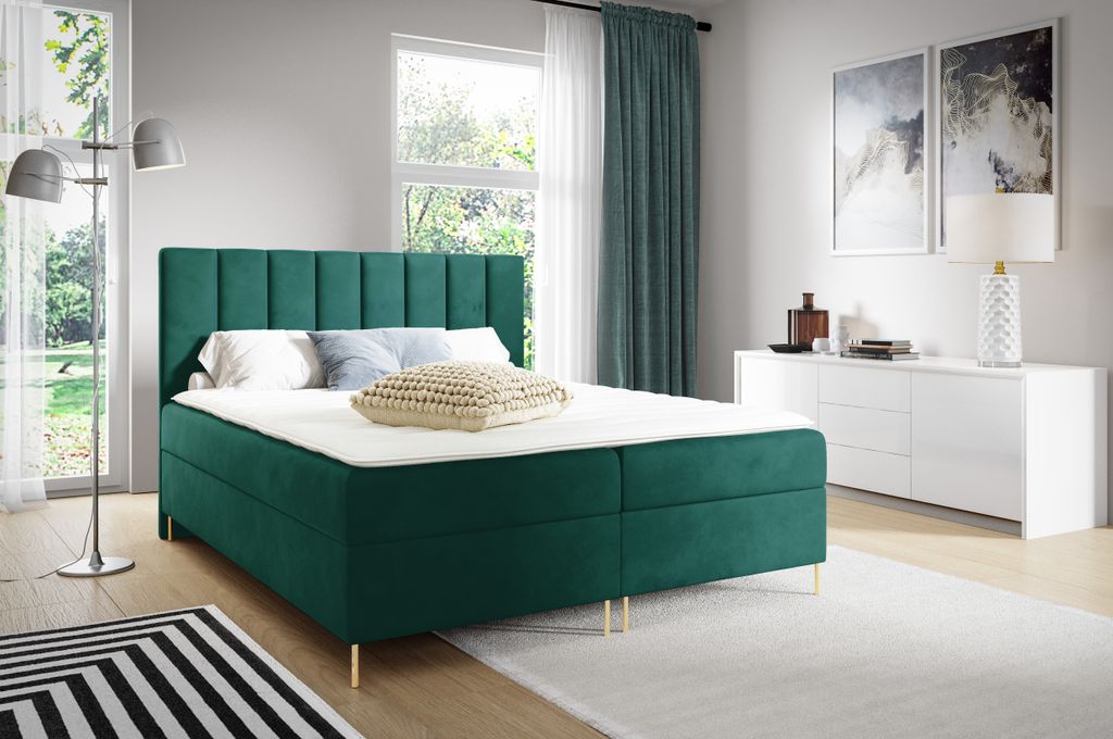 A bedroom scene with a green upholstered bed.