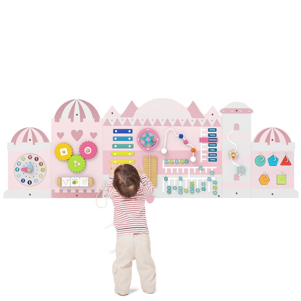 A child is interacting with a large, pink, castle-themed activity wall designed for toddlers.