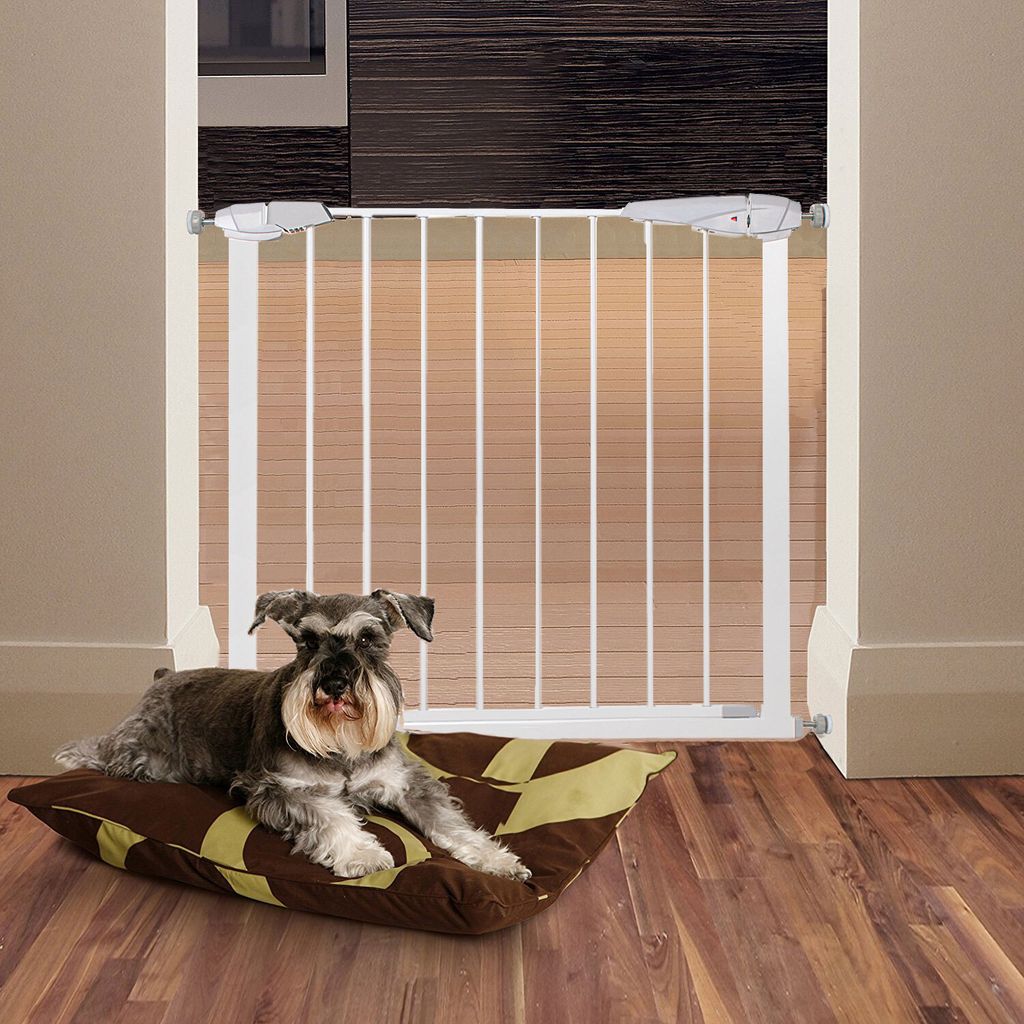 A dog is lying on a cushion in front of a white baby gate.