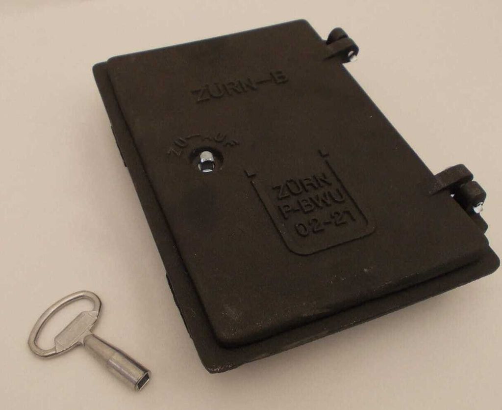 A dark gray metal chimney flap and a silver metal key are placed on a light gray surface.