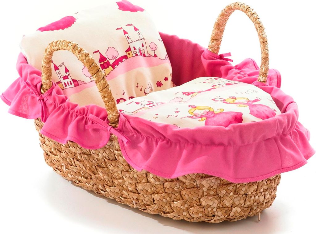 A doll's carry bag with a pink ruffled trim and a woven straw body, filled with bedding featuring a castle and princess print.