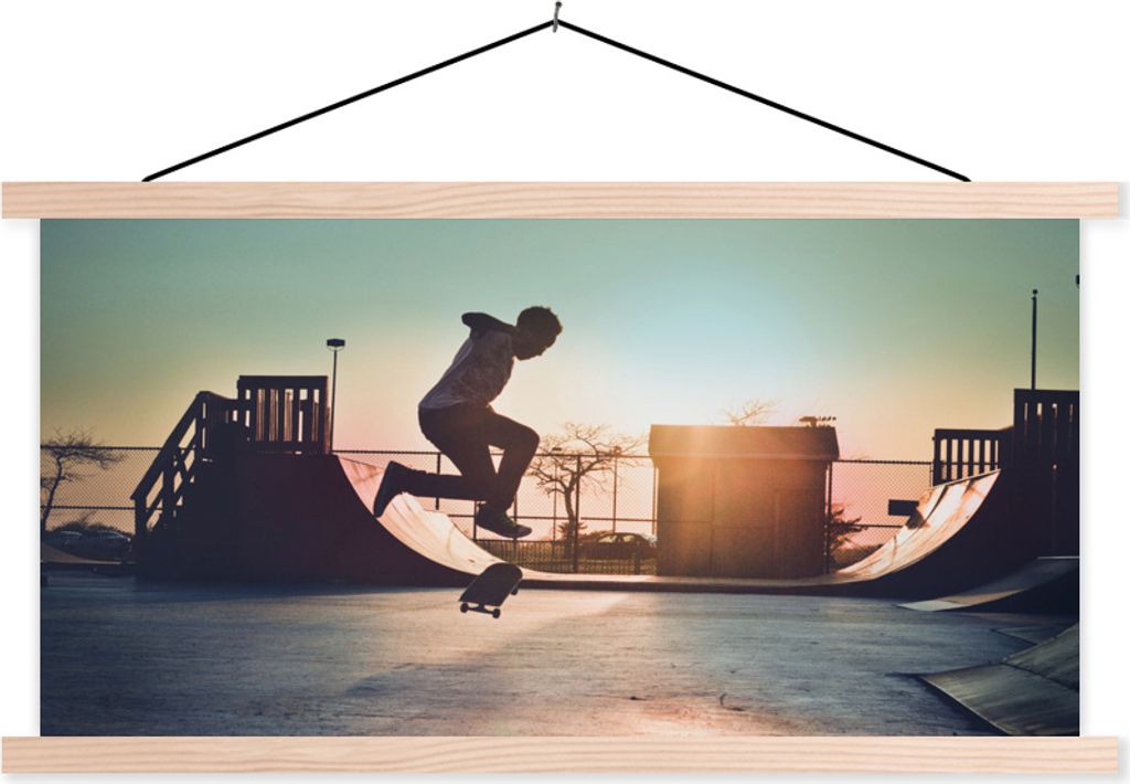 MuchoWow Textilposter Ein Junge macht bei Sonnenuntergang einen Stunt mit seinem Skateboard 120x60 cm mit holzfarbenen Rahmen - Klemmleiste
