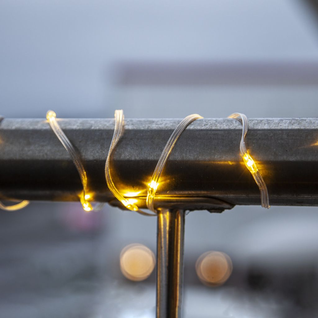 A close-up of LED string lights wrapped around a metal railing.