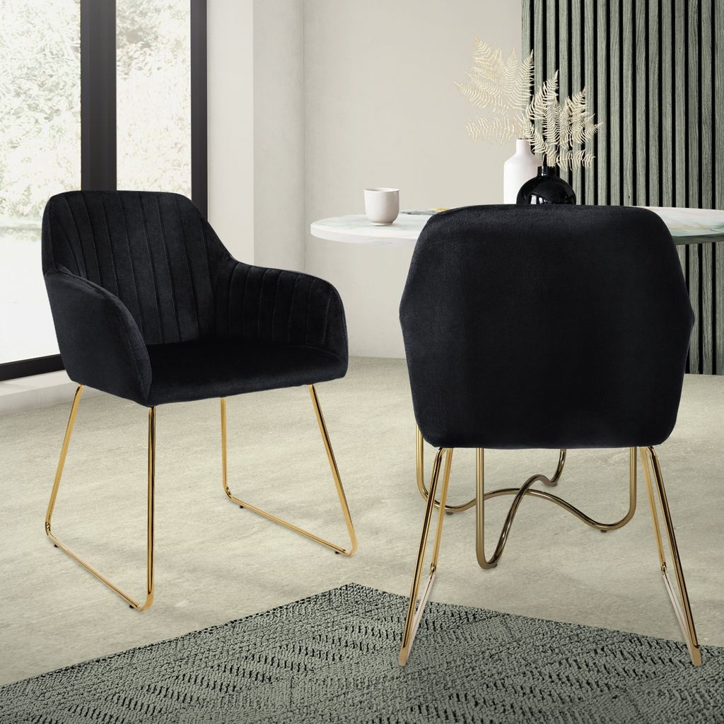 Two black velvet dining chairs with gold legs are shown in a dining room setting.