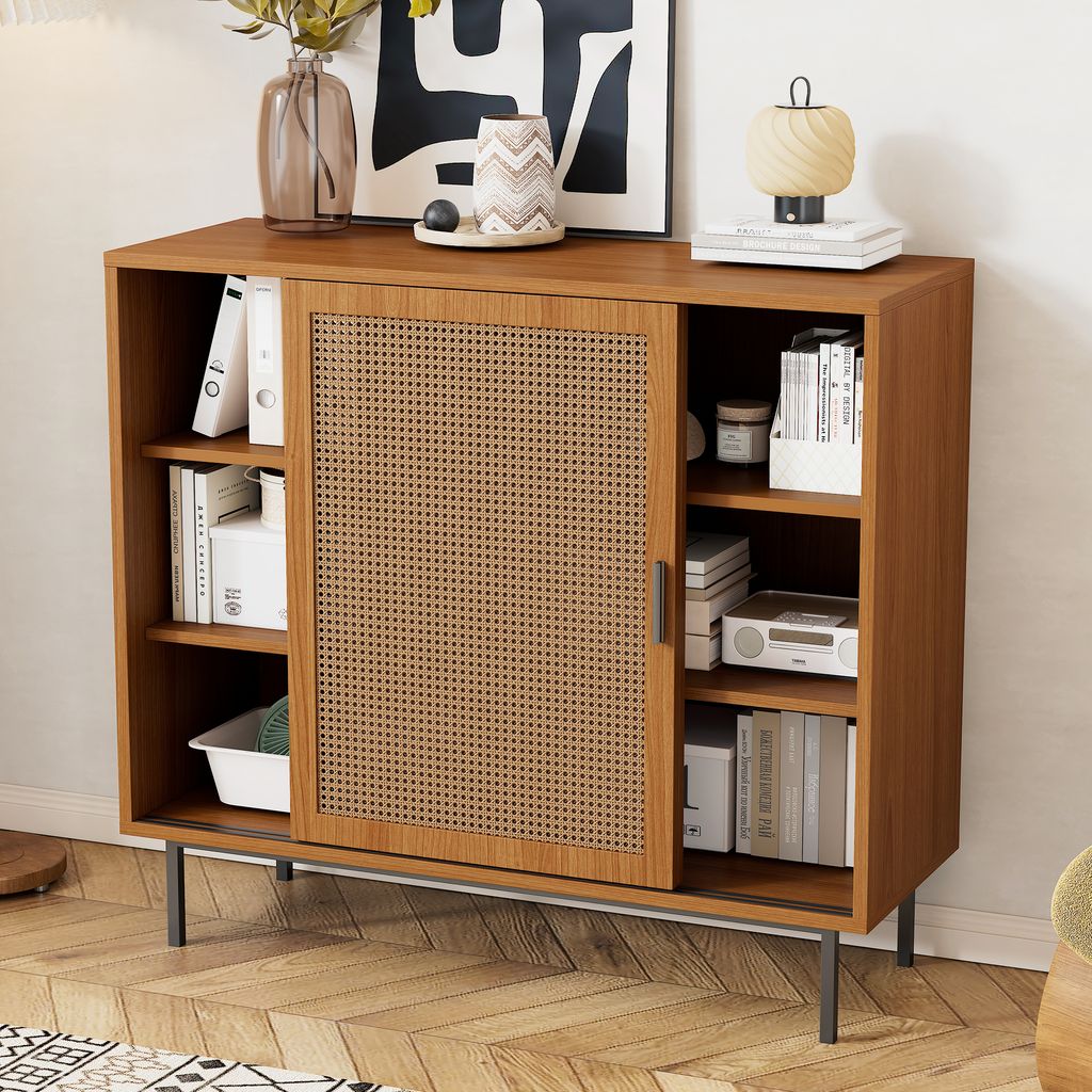 A wooden sideboard with a cane door, filled with books and decorative items, placed in a room with wooden flooring.