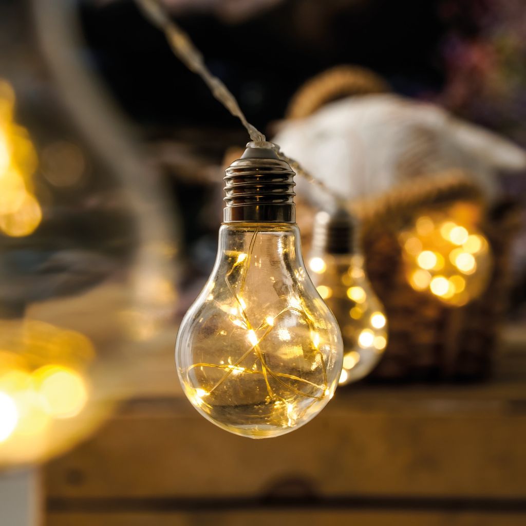 A close-up shot of a string of LED light bulbs, with a blurred background of a basket and other lights.