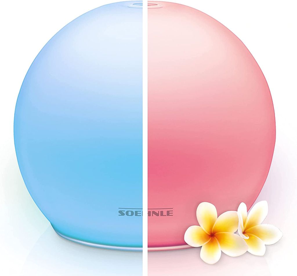 A split image of a Soehnle aroma diffuser, with one half lit blue and the other half lit pink, with two plumeria flowers in the foreground.