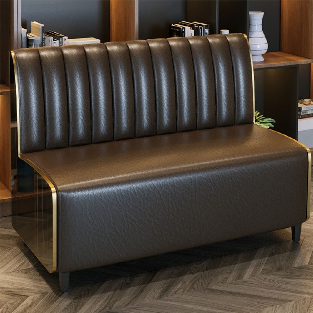 A brown leather sofa with gold trim is shown in a room with bookshelves in the background.