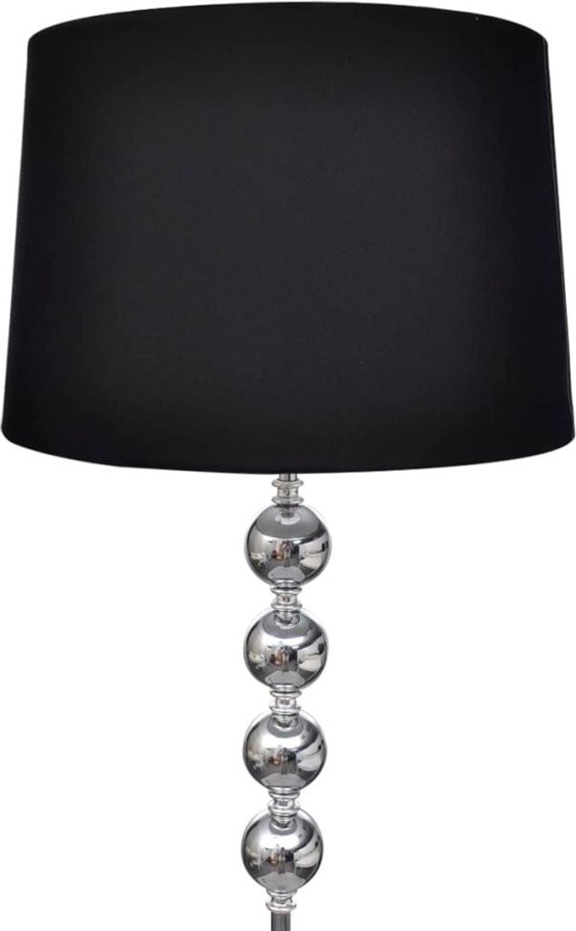 A black lampshade sits atop a silver lamp base with four decorative spheres.