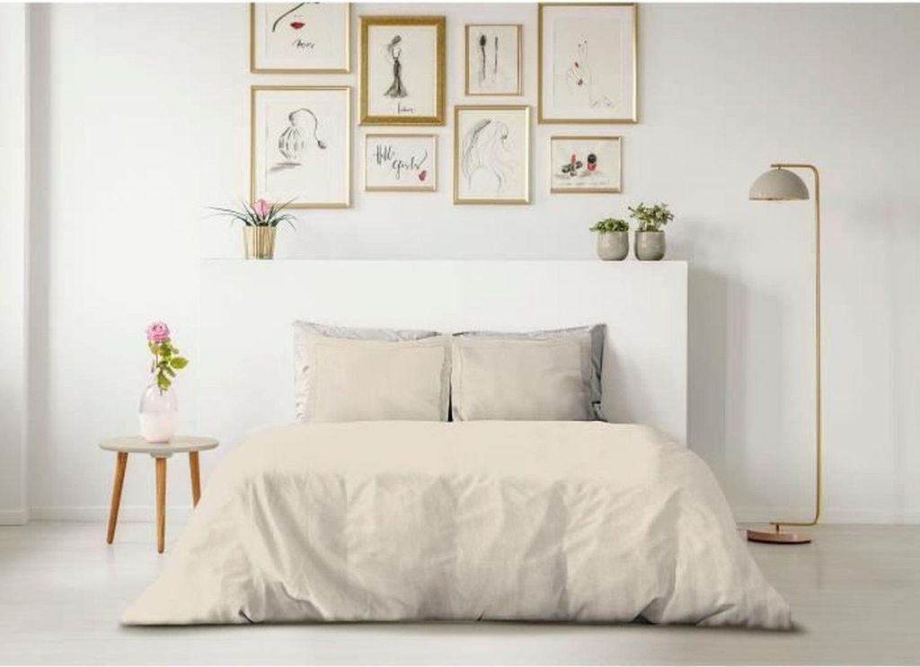 A neatly made bed with beige bedding in a room with framed art on the wall.