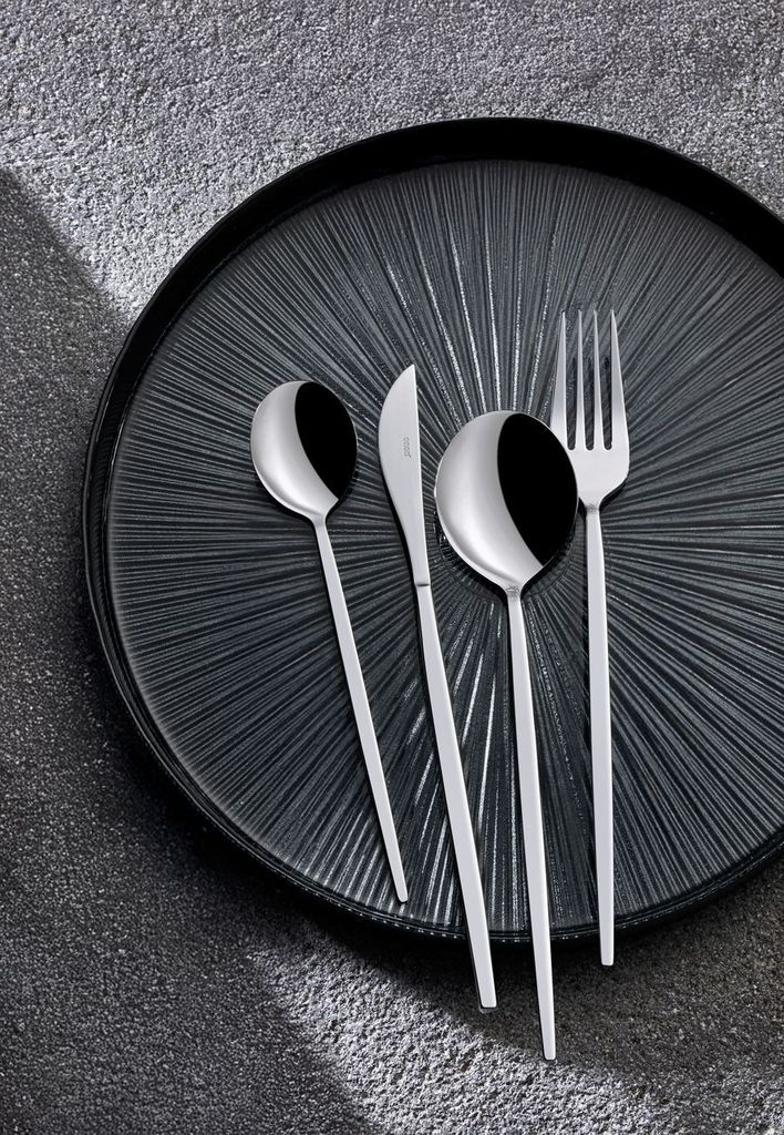 A set of cutlery on a textured black plate.
