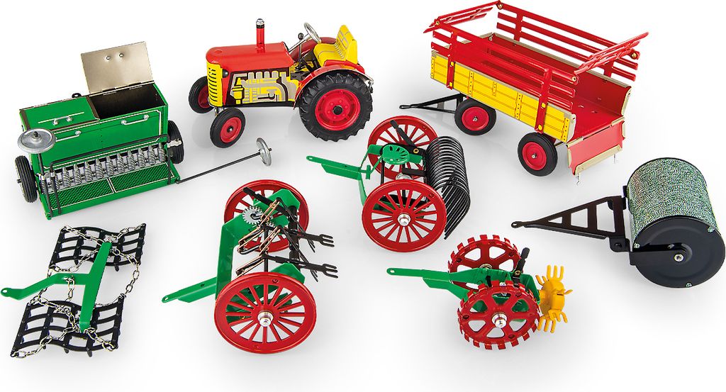 A collection of toy farm equipment, including a tractor, trailer, seeder, rake, roller, and cultivator, arranged on a white background.