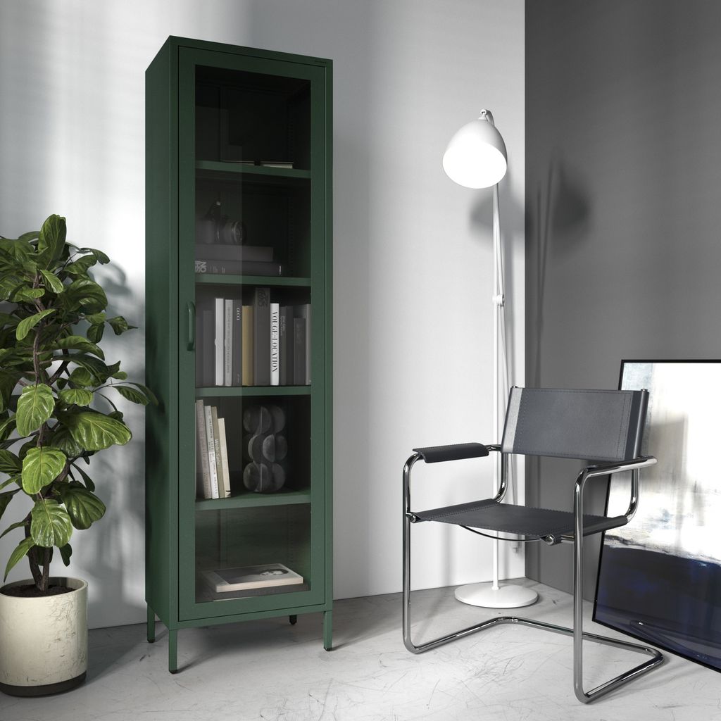 A dark green metal cabinet with glass doors stands next to a large potted plant. A modern chair and a floor lamp are also visible in the room.